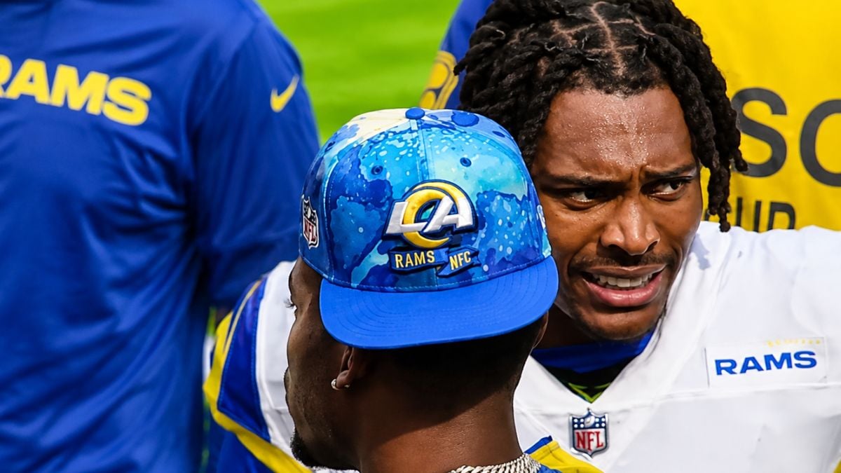 Jalen Ramsey with braids in Rams uniform leans in with intense expression while talking to teammate wearing blue LA Rams cap during mic'd up segment, sweat visible, text overlay reads "MY JERSEY DURING THE"